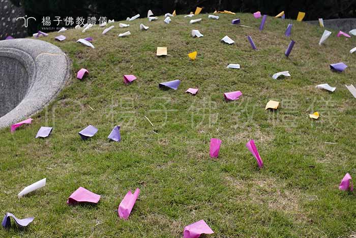 「掛紙」是將剪裁成長方形、波浪形狀的五色墓紙，依序鋪陳在墳墓四周，再以小石頭壓實，防止風吹散。象徵著對祖先的尊敬與思念，猶如古人懸掛冥錢般，是清明節祭祖儀式之一，讓慎終追遠的情懷綿延流傳。｜楊子佛教禮儀公司