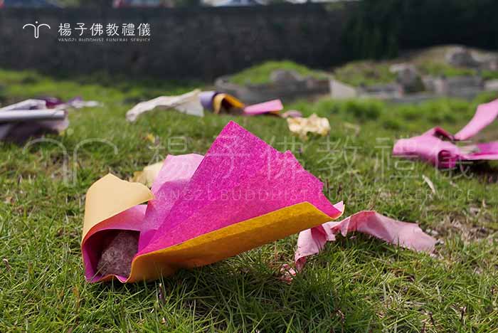 所謂「掛紙」，是將長方形、波紋狀的五色墓紙，依一定間距放置於墓地周圍，再以小石壓住，避免風吹。這個動作不只是裝飾，更象徵對祖先的敬意與懷念，就如古人懸掛冥錢，是一年一度清明祭掃的重要標誌。｜楊子佛教禮儀公司