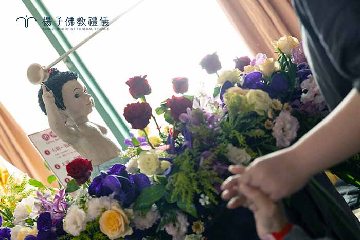為了讓無法下床的病友也能親自參與，義工細心地將行動浴佛車推至床邊。病友與家屬舀起一杓淨水灌沐如來，這一刻的畫面，展現了生命在脆弱中依然保有的尊嚴。 ｜楊子佛教禮儀公司